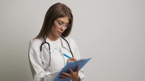 Las mujeres médico de la apariencia caucásica escribe en el papel un 4. Medicina. Sanidad — Vídeos de Stock