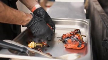 Hands of chef in black mittens close up preparing grilled peppers