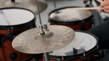 Bateristin elleri bir enstrümana vuruyor. Bir parça müzik çalar..