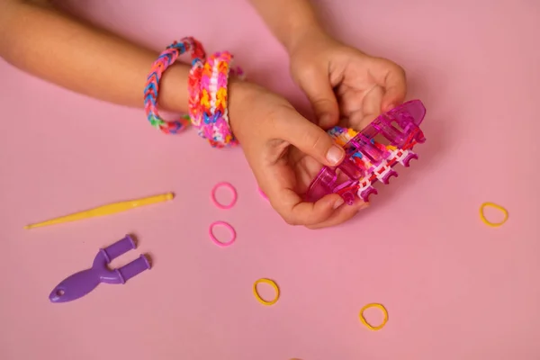 Loom for weaving toy bracelets from elastic rubber bands is held by a child in his hands. A children's hobby that develops hand motor skills. copy space