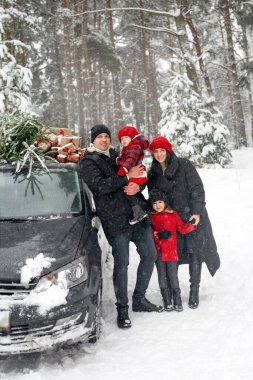 Ormanda çocuklu ebeveynler Noel ağacı ve karlı bir kış gününde kaputta hediyelerle arabanın yanında duruyorlar. Aile yeni yılı kutlamaya hazırlanıyor. Noel 'in sembolü