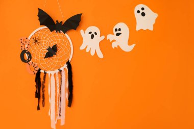 Örümcek ağlı, örümcekli ve yarasalı bir düş kapanı turuncu bir arka planda hayaletli bir cadılar bayramı konseptidir. Kartpostallar ve tatil posterleri.