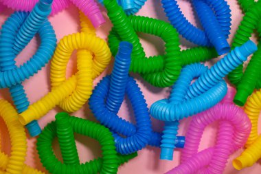 Pembe arka planda bir sürü parlak renkli oyuncak tüpleri var. Eğlenceli, komik, duyusal bir oyuncak. Detayları birbiriyle bağlantılı.