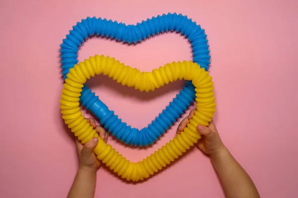 Enfant Tient Dans Ses Mains Cœur Fait Tubes Pop Ondulés — Photo