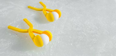 İki sarı oyuncak kar topu buz pistinde aletler yapıyor. Kış çocukların açık hava oyunları. Kartopu savaşı. Kopyalama alanı olan pankart