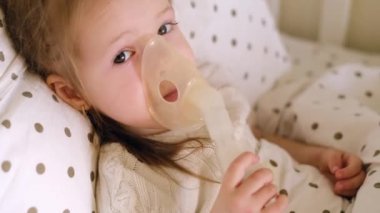 Bebek battaniyenin altında yatar ve nebulizör maskesinin içine nefes alır, buharın çıktığı yere. İlaçlarla solunumu. 