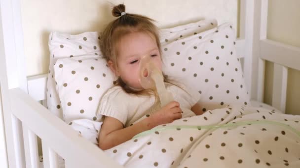 生病的孩子躺在床上 躺在毯子下 呼吸在吸入面罩里 吸入治疗咳嗽 肺炎或哮喘的药物 治疗和照顾一个不健康的婴儿 可爱的两岁女孩 — 图库视频影像