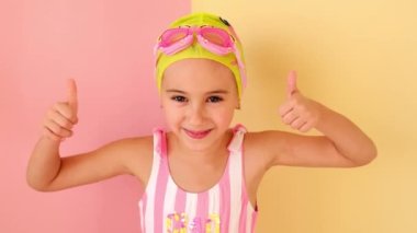 Havalı mayo giyen, bilardo şapkası takan, başarılı bir jest yapan ve aferin diyen oldukça olumlu bir kız. Pembe-sarı stüdyo arka planı. Süper havalı yüzme