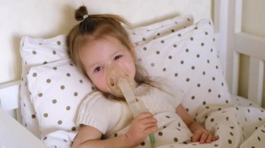 Yorgun bebek solunum maskesiyle yatakta yatıyor. Engelleyici bronşit tedavisi için buhar soluyor. Atopik deri iltihabının şiddetlenmesi sonucu bir çocuğun ellerinde yara var.