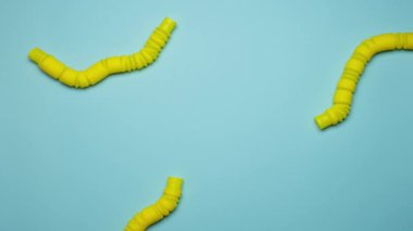 Oluklu sarı pop tüplü oyuncaklar yavaşça emekler ve arka planda gülen bir yüz şeklinde bağlanırlar. Popüler yeni moda oyuncaklar. Hayal gücüyle oynamak. Olumlu düşün.. 