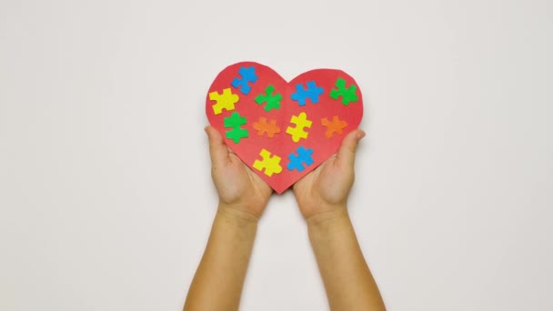 支援の概念 自閉症症候群の子供を持つ家族のケアと団結 大人と子供の手の中にさまざまな色のパズルで心 母と父への愛 世界自閉症の日 — ストック動画