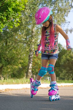 Pembe örgü saçlı, miğferinde rastalı saçları, koruyucu dirseklikleri ve dizlikleri olan bir kız şehirde asfalt yollarda paten kanyonlarına biniyor. Çocuk patenciler için koruyucu ekipman