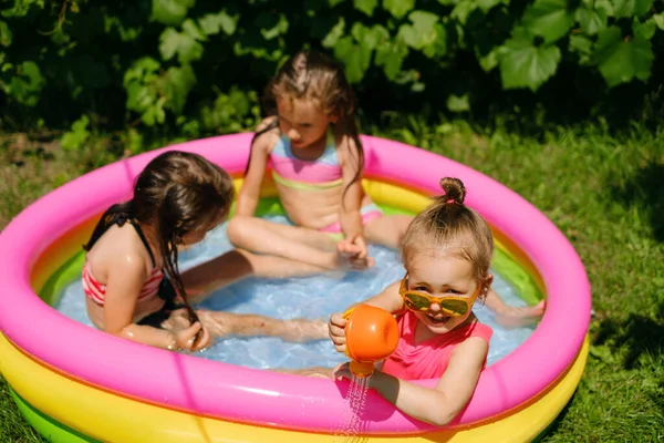 정원에 부풀어 오르는 수영장에서 소녀가 즐거운 시간을 보내고 아이들 속에서 스톡 사진