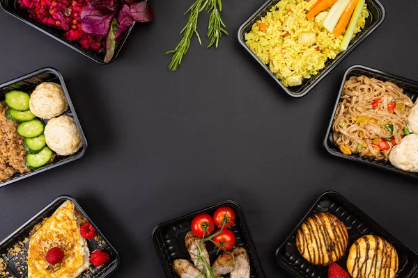 Sağlıklı yemek servisi menüsünü beslenme çantalarında hazırla et ve sebze paketleri siyah masa arkasında.