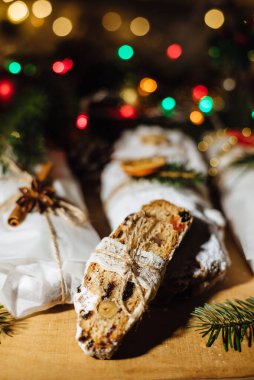Tahta arka planda çalınmış bir Noel. Geleneksel Noel Almancası, şenlikli tatlı. Kurutulmuş meyveli Noel pastası, Noel ağacının arka planında zencefilli kurabiye. Seçici odak