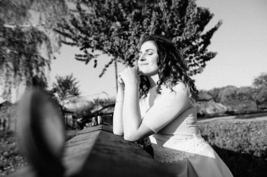 Kıvırcık esmer kadın gözlerini kapatıyor, yaz gününde güneşin tadını çıkarıyor. Gülümseyen güzel bir kızın portresi. Siyah beyaz fotoğraf