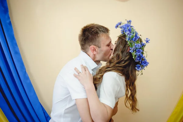 Beautiful couple in love kissing on the background of the Ukrainian yellow and blue flag. Members of the Kyiv territorial defense married in under the laws of martial law. War and love Ukraine