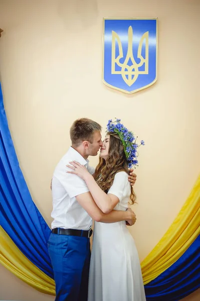 Beautiful couple in love kissing on the background of the Ukrainian yellow and blue flag. Members of the Kyiv territorial defense married in under the laws of martial law. War and love Ukraine