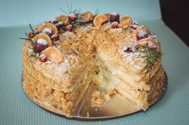 Napolyon 'un pastası, mandalin, üzüm, köknar dalları ve daha briyantinden oluşan yeni yıl kompozisyonu ile süslenmiştir. Mavi arka planda bir yaprak keki.