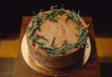 Kızılcıkla süslenmiş lezzetli çikolatalı pasta. Kahverengi arka planda yuvarlak kremalı pasta..