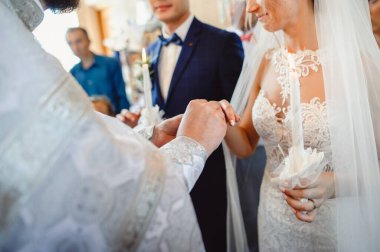 Ortodoks kilisesinde dini nikah. Evlilik bağıyla. Alyanslarınızı takın. Rahip, gelin ve damat parmaklarına altın alyans takıyor..