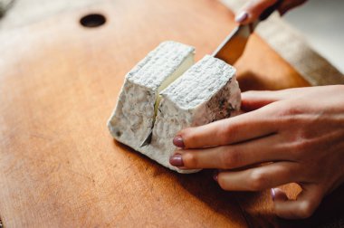 Tahtadaki Valencay peyniri. Peynir üreticisi peyniri mavi küfle keser, yakın plan. Keçi sütünden Fransız yumuşak peyniri. Peynir kompozisyonu. Uzayı kopyala Metin için yer.
