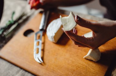 Peynir üreticisinin ellerinde bir parça camembert peyniri, yakın plan. Beyaz küflü yumuşak Fransız peyniri tatmış bir kadın..