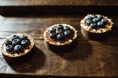 Koyu ahşap arka planda yaban mersinli çikolatalı turtalar. Tatil masası için güzel porsiyon kekler. Taze yaban mersinli tatlı.
