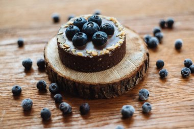 Tahta arka planda taze yaban mersinli ve çikolatalı lezzetli tart. Moda bir tatlı. Üst görünüm