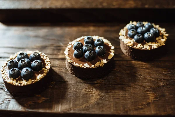 Koyu ahşap arka planda yaban mersinli çikolatalı turtalar. Tatil masası için güzel porsiyon kekler. Taze yaban mersinli tatlı.