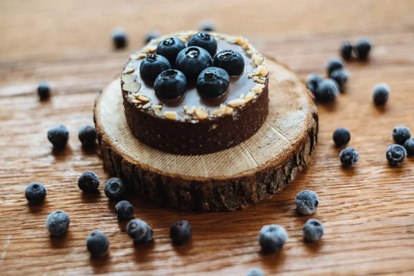 Tahta arka planda taze yaban mersinli ve çikolatalı lezzetli tart. Moda bir tatlı. Üst görünüm