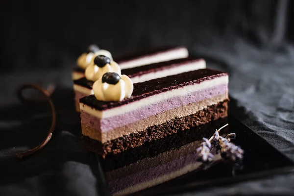 Three chocolate cakes on a black background. Mousse cake with blueberries. Opera cake at the a La carte desserts , cakes on a black background. Selective focus