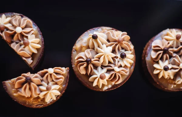 Tuzlu karamel, fındık ve kremalı çörekler. Siyah arka planda izole edilmiş tatlı çikolatalı kekler. Çikolatalar için modern mini tatlılar, partiler. Yukarıdan görüntüle