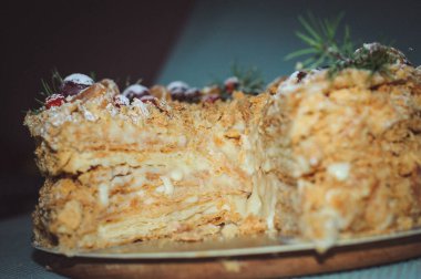 Napolyon 'un pastası, mandalin, üzüm, köknar dalları ve daha briyantinden oluşan yeni yıl kompozisyonu ile süslenmiştir. Mavi arka planda bir yaprak kek, yakın plan..