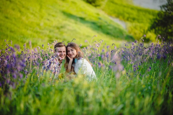 青い花の間の美しい芝生の上で男と女の肖像画 ラブストーリー 屋外で笑っているカップルを愛し — ストック写真