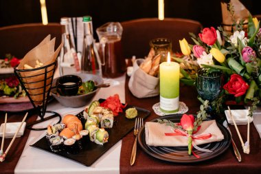 Şölen masasındaki bir restoranda suşi. Tabaklar, çatal bıçaklar ve abur cuburlarla dolu şenlik masası. Zarif bir sofra..