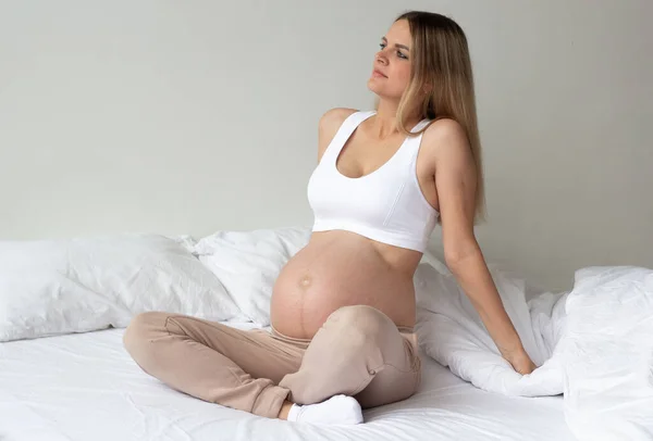 Roztomilá Blondýnka Sedí Doma Posteli Světlém Pozadí Portrét Měsíců Těhotenství — Stock fotografie