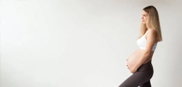 一个漂亮的金发怀孕女孩站在一个白色背景的个人资料 肚子饿特写 复印酶 — 图库照片