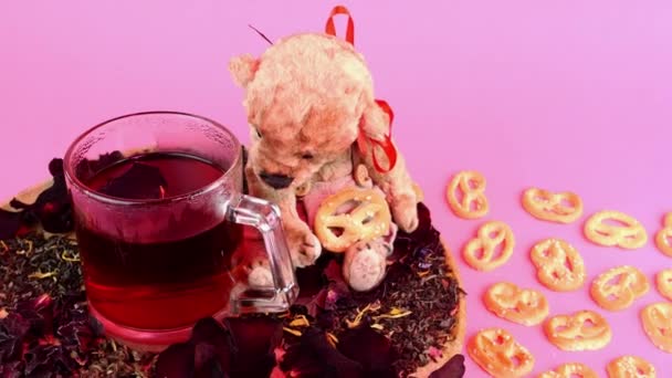 Flower tea in glass mug and teddy bear slowly rotates in pink lighting on pink background. — 비디오