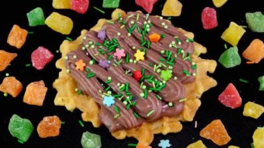 Liege waffles decorated with chocolate cream and sprinkled with sweets and candied fruits rotate.