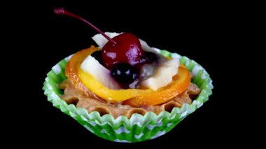 Vişneli kremalı kek, böğürtlen, siyah arka planda meyveler yavaşça döner.