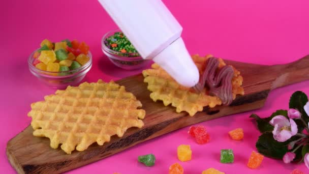 Liege waffles decorated with chocolate cream and sprinkled with sweets next to candied fruits. — Stock video