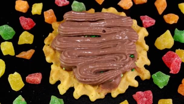 Liege waffles decorated with chocolate cream and sprinkled with sweets and candied fruits rotate. — Stok video