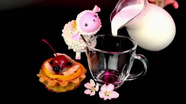 Cream cupcake with cherry, berry, fruits and apple flowers on black background. Milk is poured into transparent cup. — Stock video