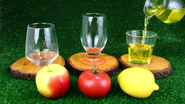 Riempimento di bicchieri trasparenti con diversi succhi di frutta e frutta vicino. Le bevande di frutto sane di vitamina sono versate in occhiali. — Video Stock