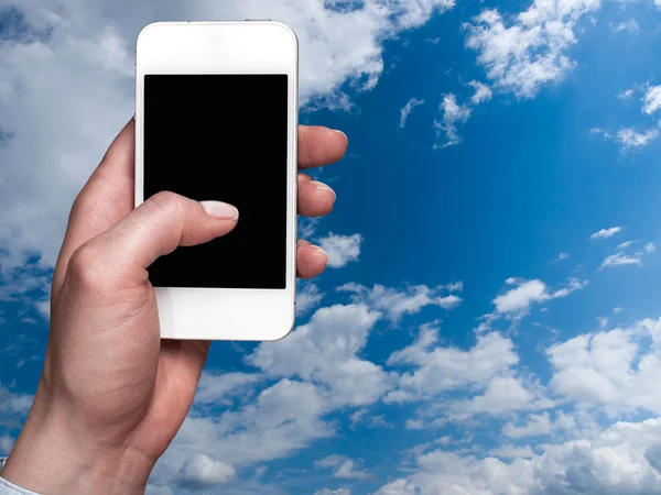 Smartphone realizada na mão sobre um fundo do céu — Fotografia de Stock