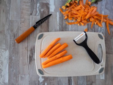 Sebze ve meyve soymak için bıçağın yanında soyulmuş havuçlar, yukarıdan çekilmiş bir fotoğraf, yiyecek konsepti.