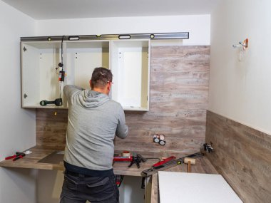 Caen, Fransa Şubat 2022. Marangoz mutfak mobilyalarını ve dolaplarını monte eder. Mutfakta profesyonel mobilya toplantısı var.