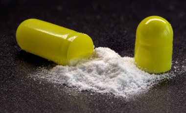 kapsüller tabletler - siyah arkaplan üzerine serpiştirilmiş beyaz toz, makro fotoğraf