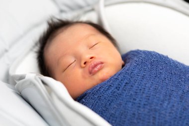 Sevimli, uyuyan yeni doğmuş bebek bebek, bebek yatağının üzerinde mavi bir sargı bezi ile rahatla. Yeni doğmuş bebek fotoğraf konsepti.